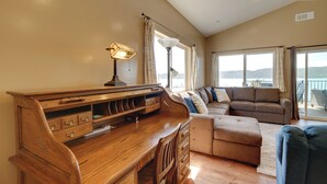 A spacious living room with a wooden desk, a sofa, and a view of the sea. - Clearlake Vacation Rental w/ Nearby Lake Access! (Clearlake)
