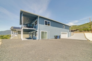 A two-story building with a covered outdoor area, a garage, and a view of mountains.