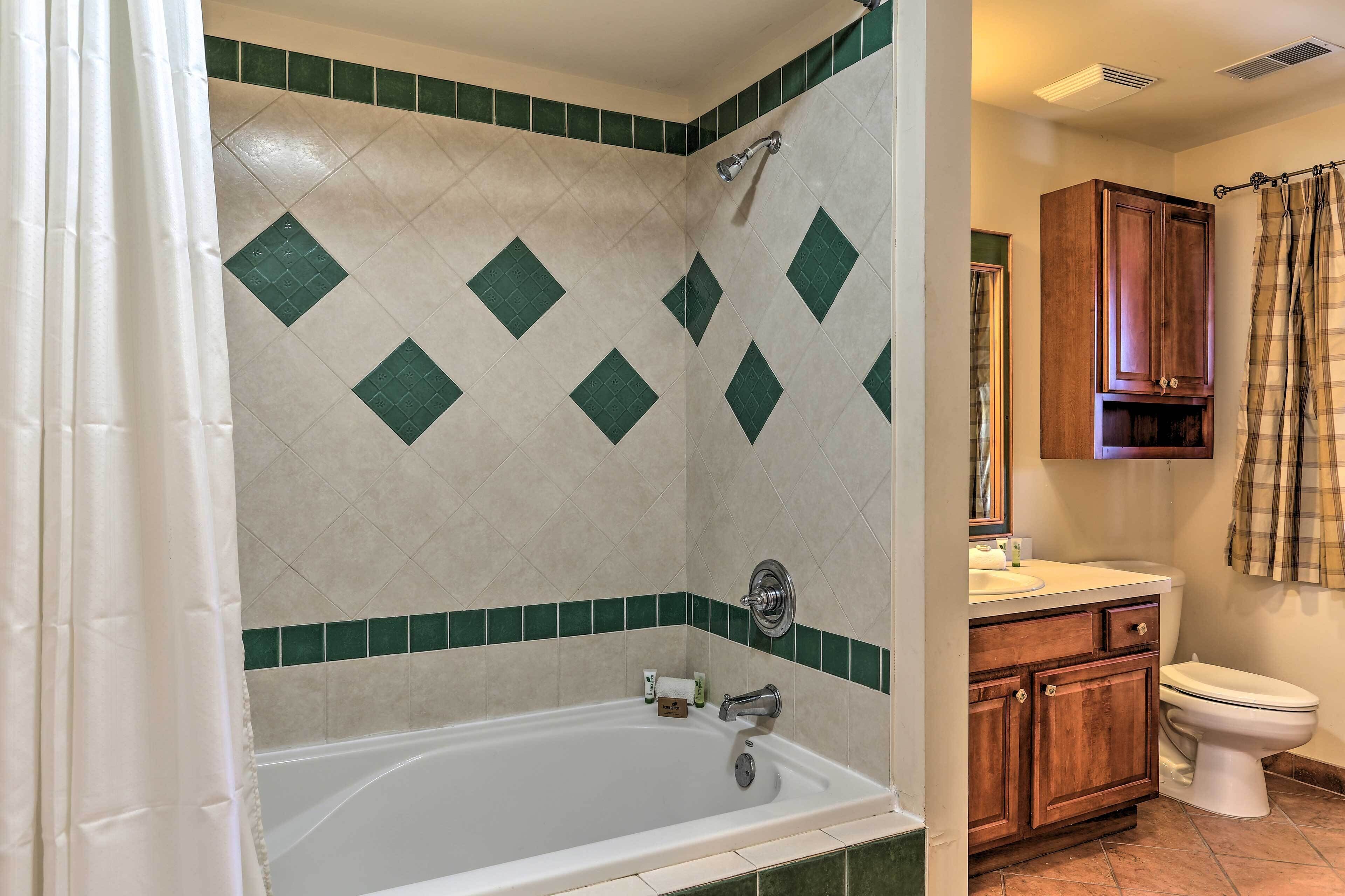 A bathroom with a bathtub, a toilet, and wooden cabinets.