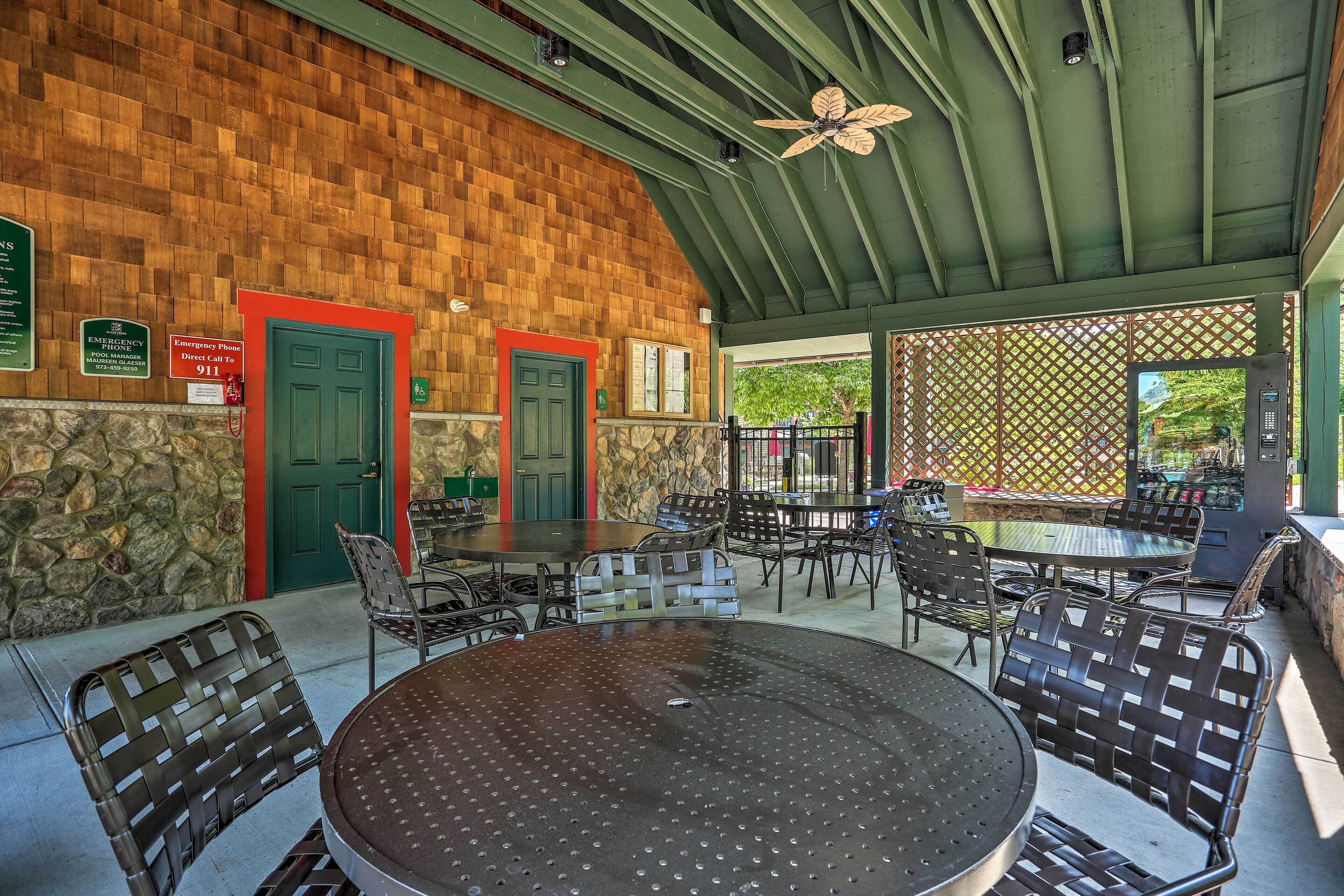 An outdoor patio area with stone walls, green doors, and metal furniture.