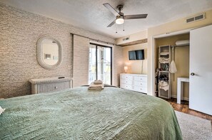 A bedroom with a large bed, a ceiling fan, a mirror, a wardrobe, and a television on the wall. - Coastal Condo w/ Pool Access - Steps to Beach (Carolina Beach)
