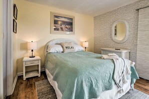 A bedroom with a bed, two bedside tables, a nightstand, a mirror, and a wall with a textured pattern.