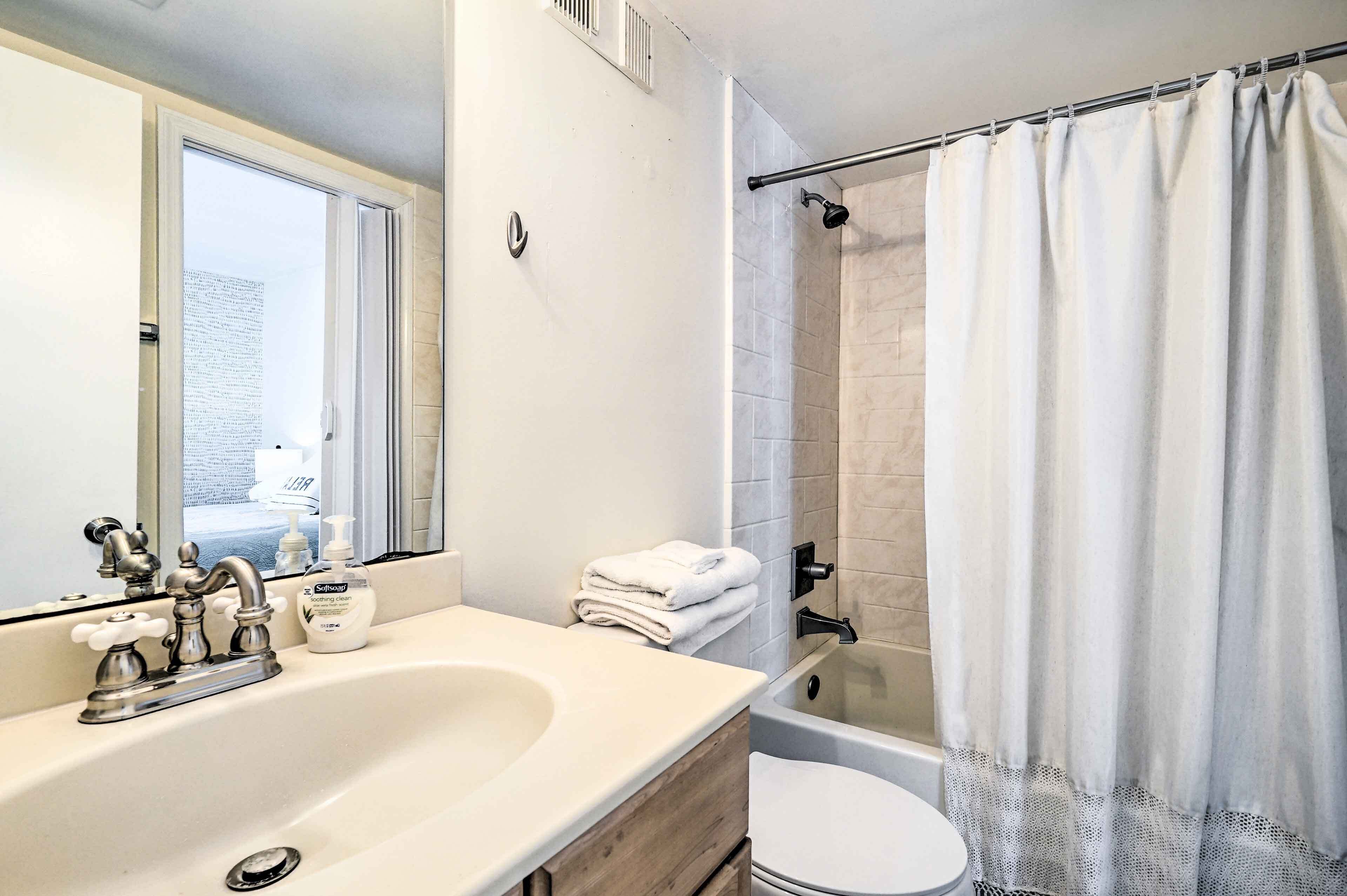 Une salle de bain équipée d’un lavabo, d’un miroir, de toilettes et d’un espace douche.