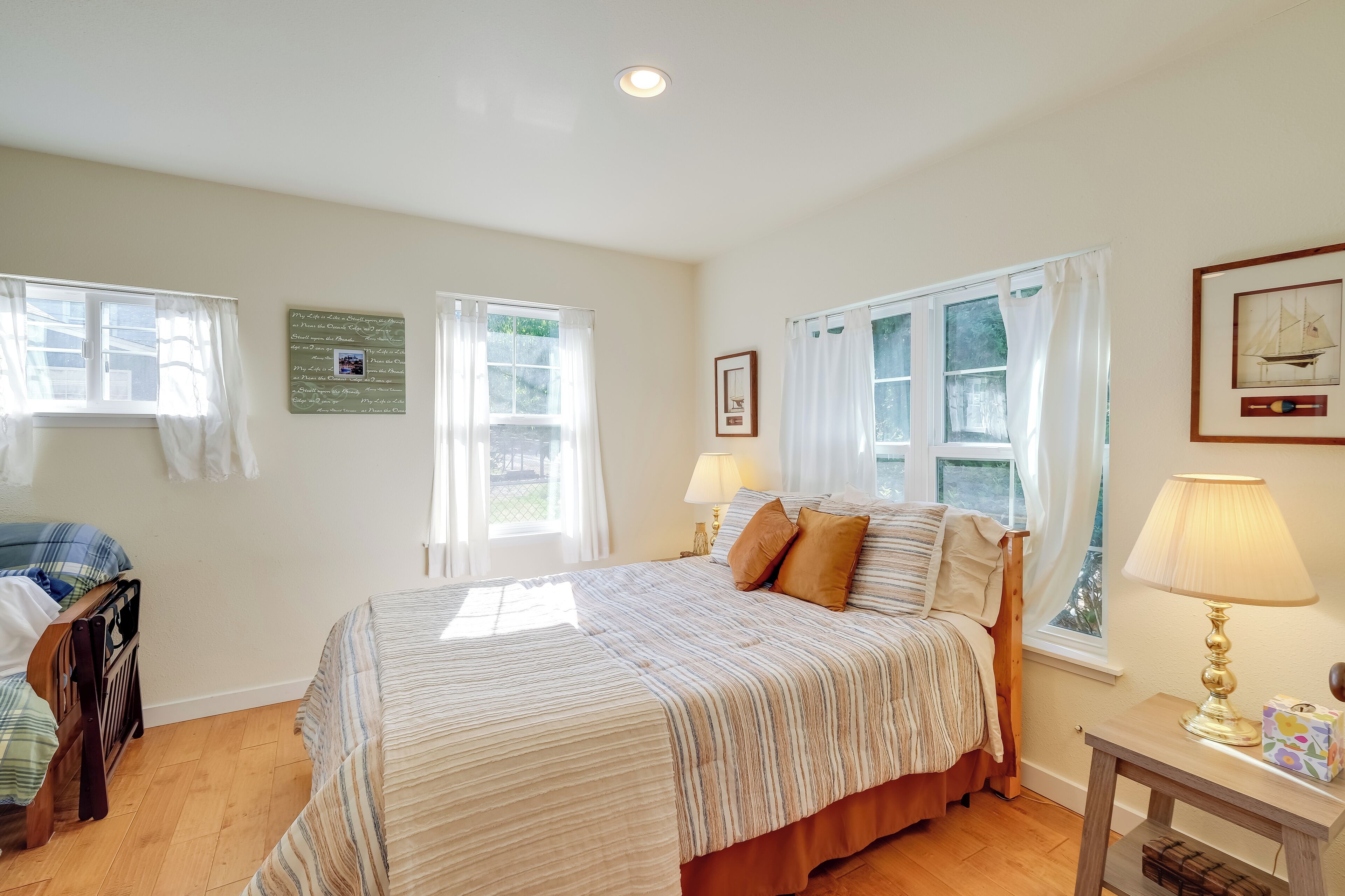 A bedroom with a large bed, two bedside lamps, a nightstand, and a window with curtains.