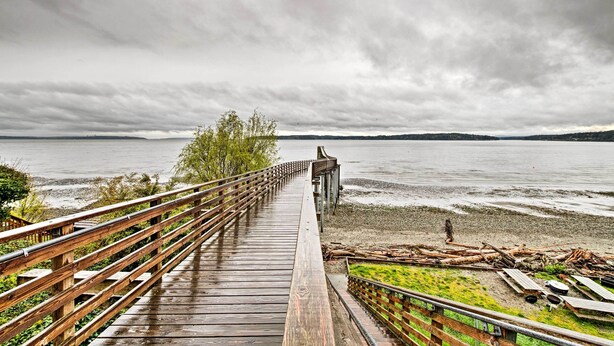 A wooden boardwalk leading to a beach with a view of the water and distant land. - Charming Indianola Home: Walk to Town! (Indianola)