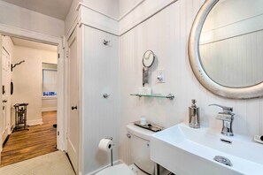 A bathroom with a white sink, a round mirror, and a toilet.