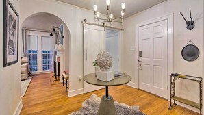 A hallway with a chandelier, a white door, and a fireplace.