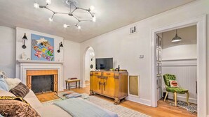 A living room with a fireplace, a green velvet armchair, and a patterned rug.