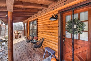 A wooden cabin with a porch, rocking chairs, and a table with chairs.