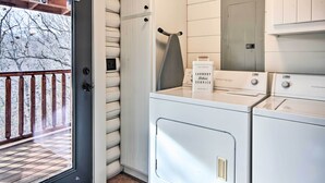 Un espace buanderie avec une porte donnant sur un balcon, un étendoir et des paniers à linge empilés.