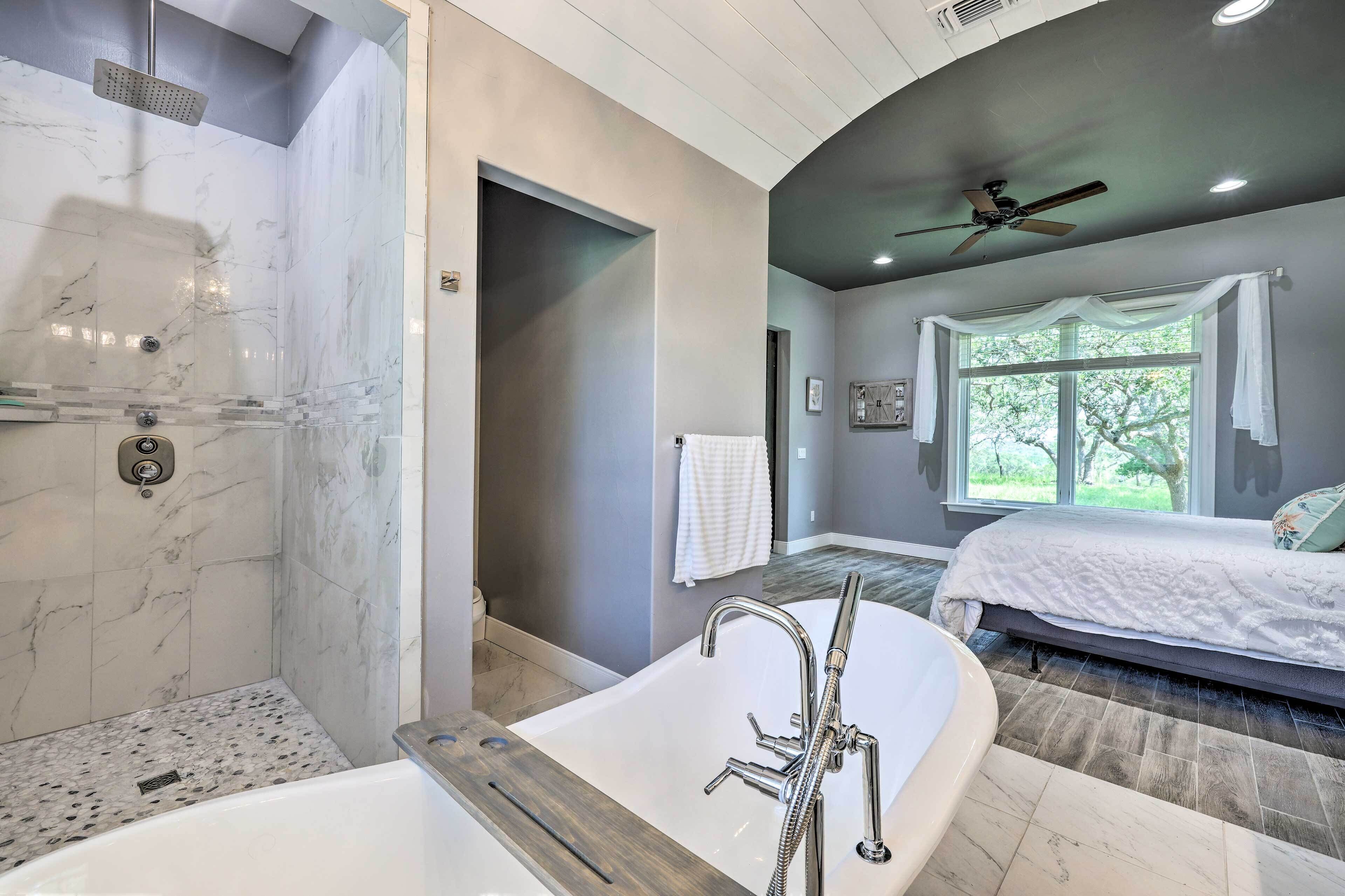 Ein modernes Badezimmer mit freistehender Badewanne, einer Dusche mit Regendusche und einem großen Fenster für natürliches Licht.