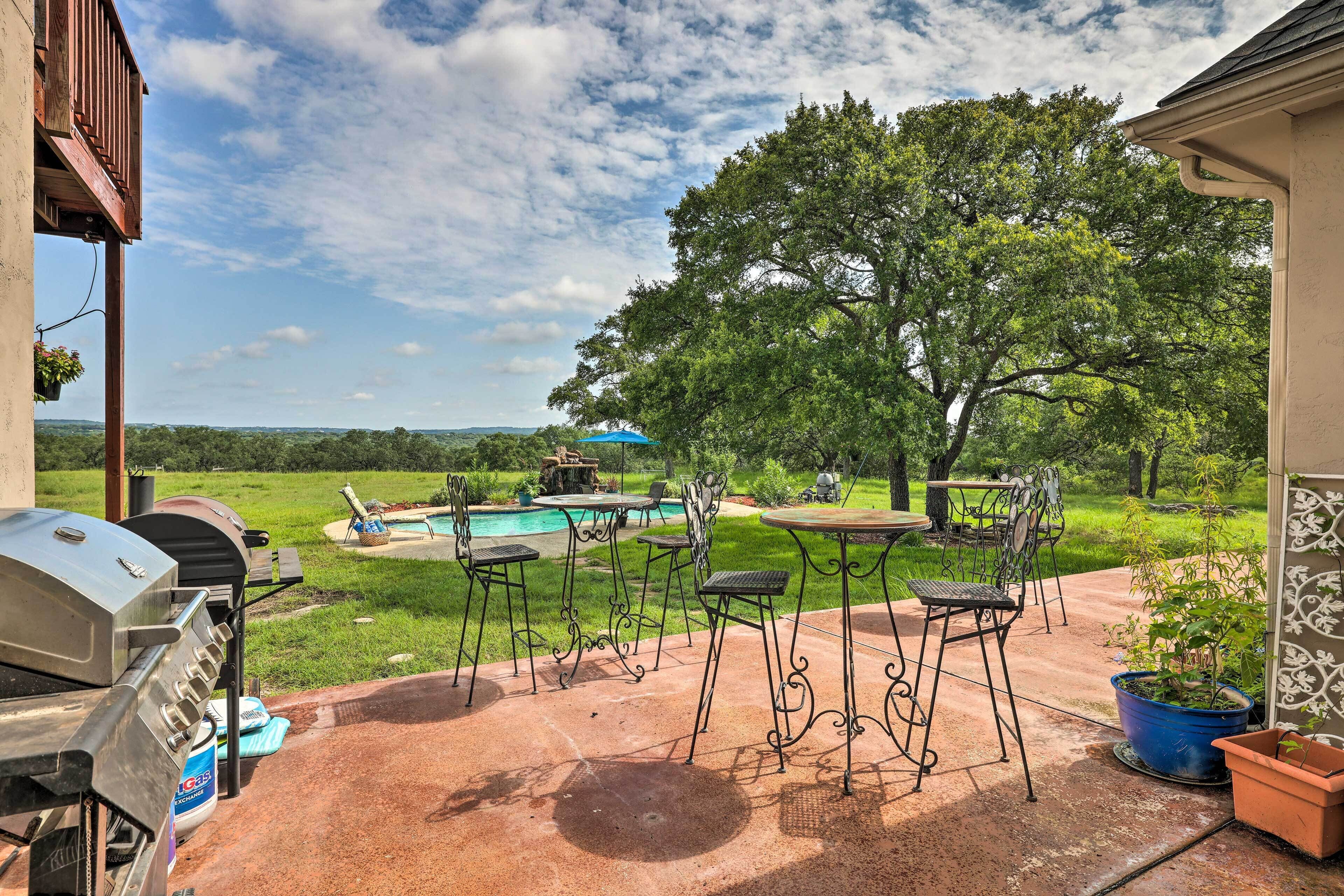 A patio with a barbecue grill, outdoor seating, and a swimming pool.