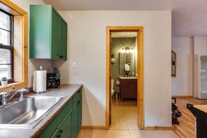 A kitchen with green cabinets, a stainless steel sink, and a wooden countertop. - Steps to Main Street! Cozy Red River Getaway (Red River)
