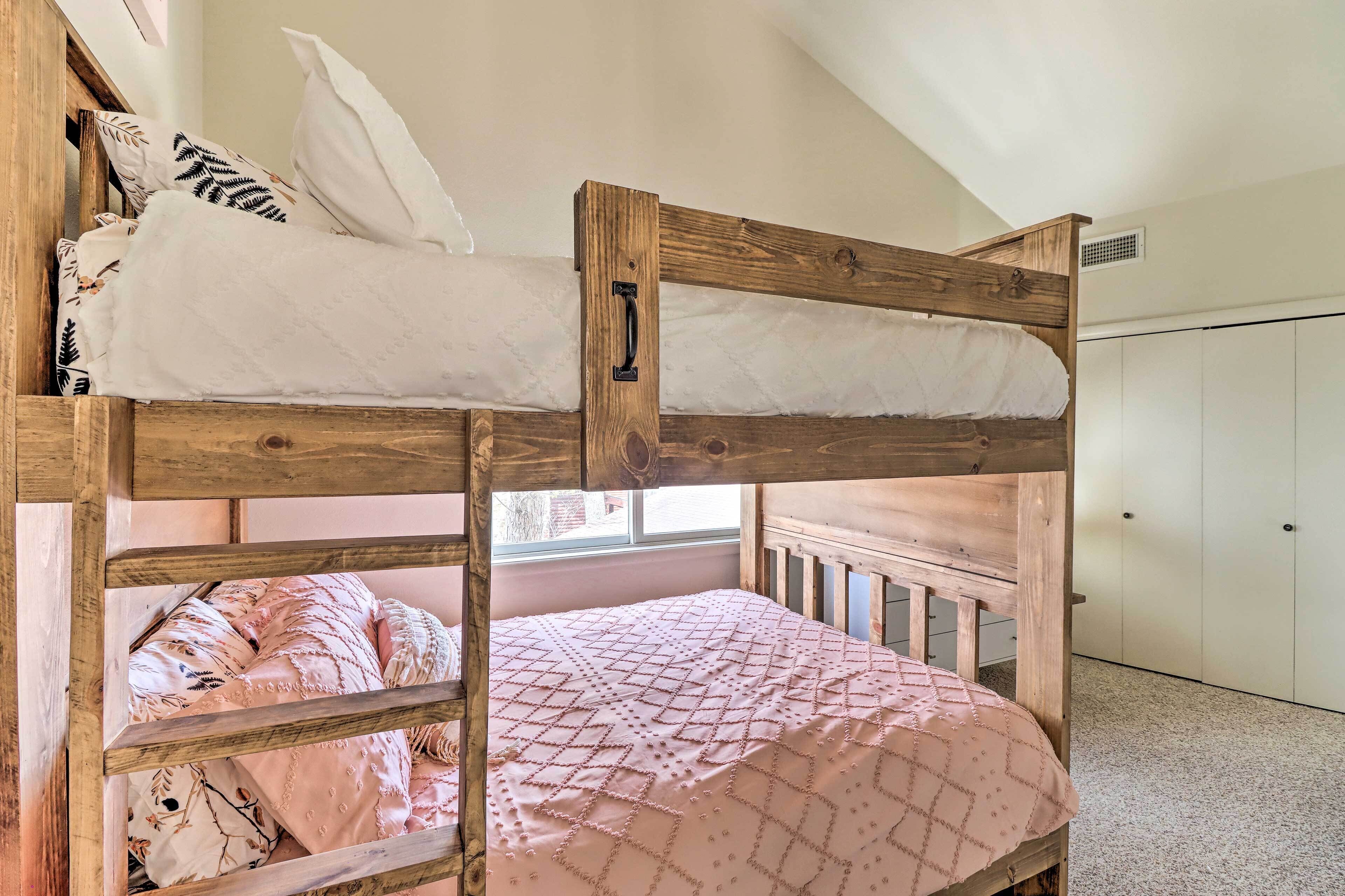 A bunk bed with a wooden headboard, a pink quilt, and a white pillow.
