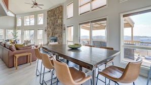 Un comedor amplio con una gran mesa de madera, sillas de cuero y una pared decorativa de piedra.