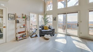 Un salón amplio con un sofá gris, una estantería y un ventanal con vistas a una terraza.