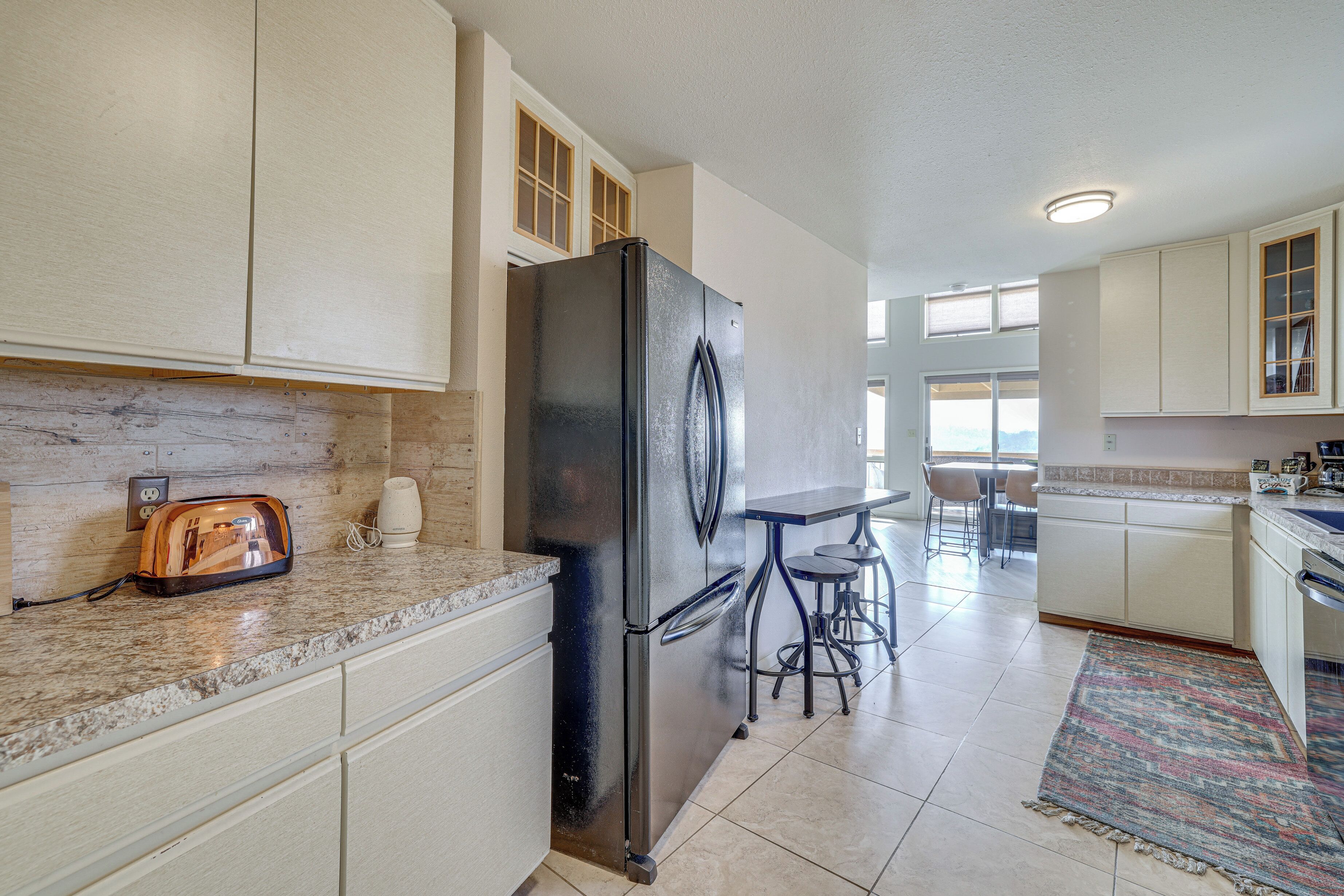A kitchen with a stainless steel refrigerator, a toaster, and a bar stool.