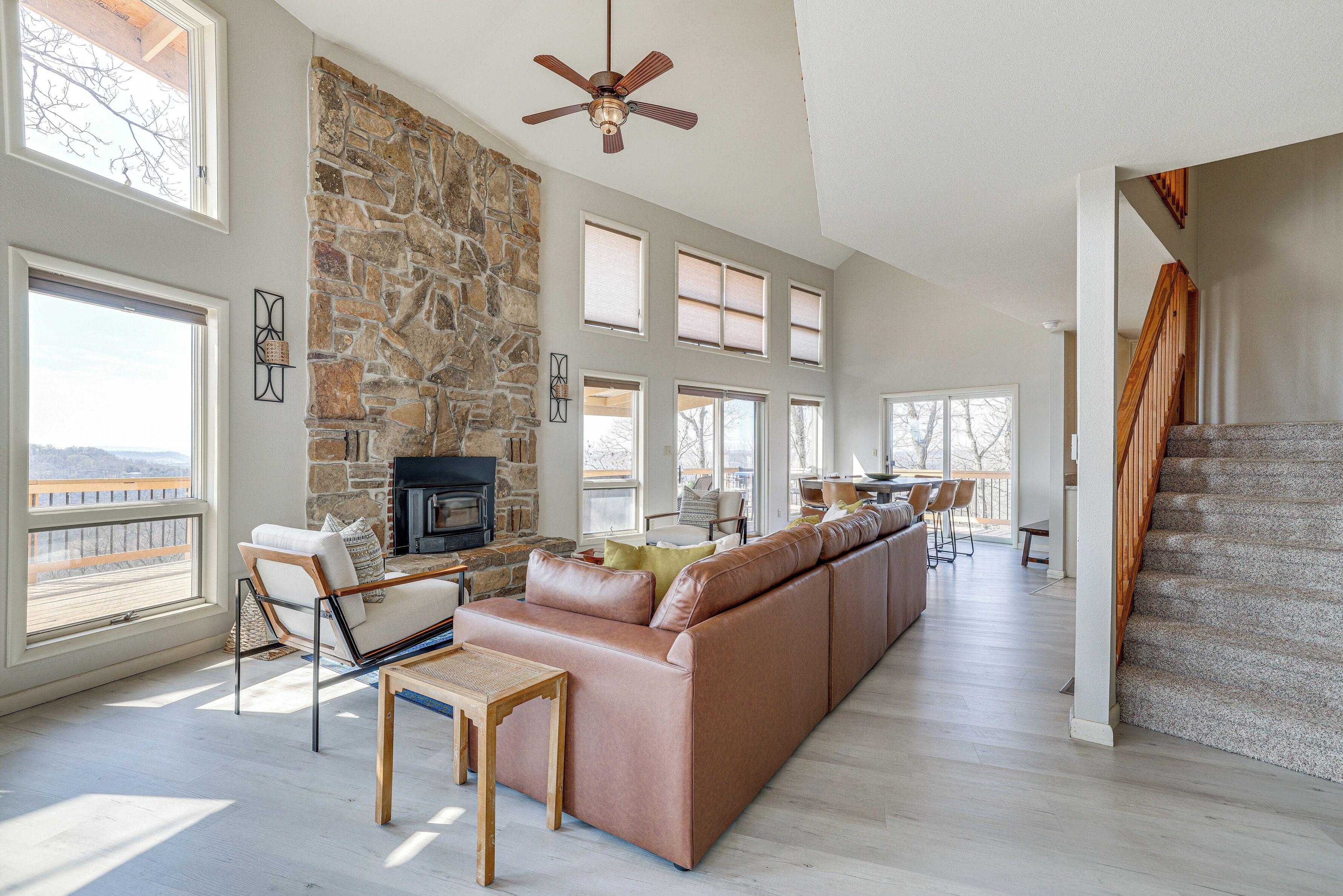A spacious living room with a stone fireplace, a large sofa, and a dining area with a view.