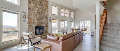 A spacious living room with a stone fireplace, a large sofa, and a dining area with a view.
