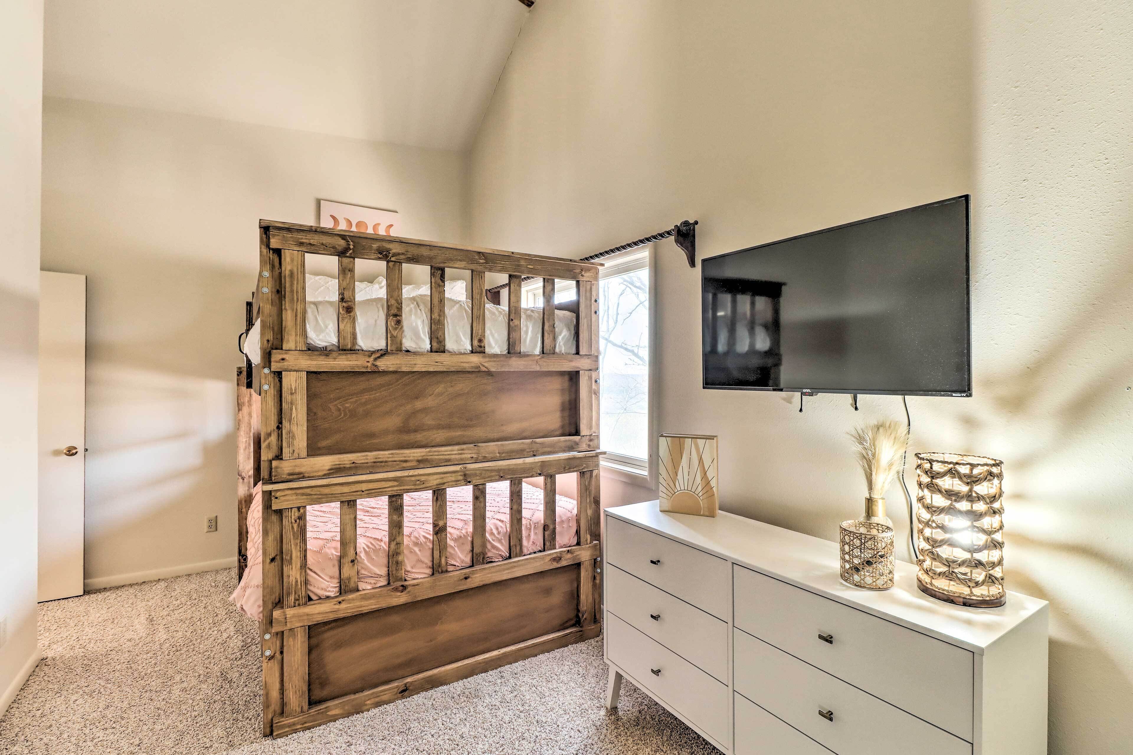 A bedroom with a bunk bed, a dresser, a TV, and a window.