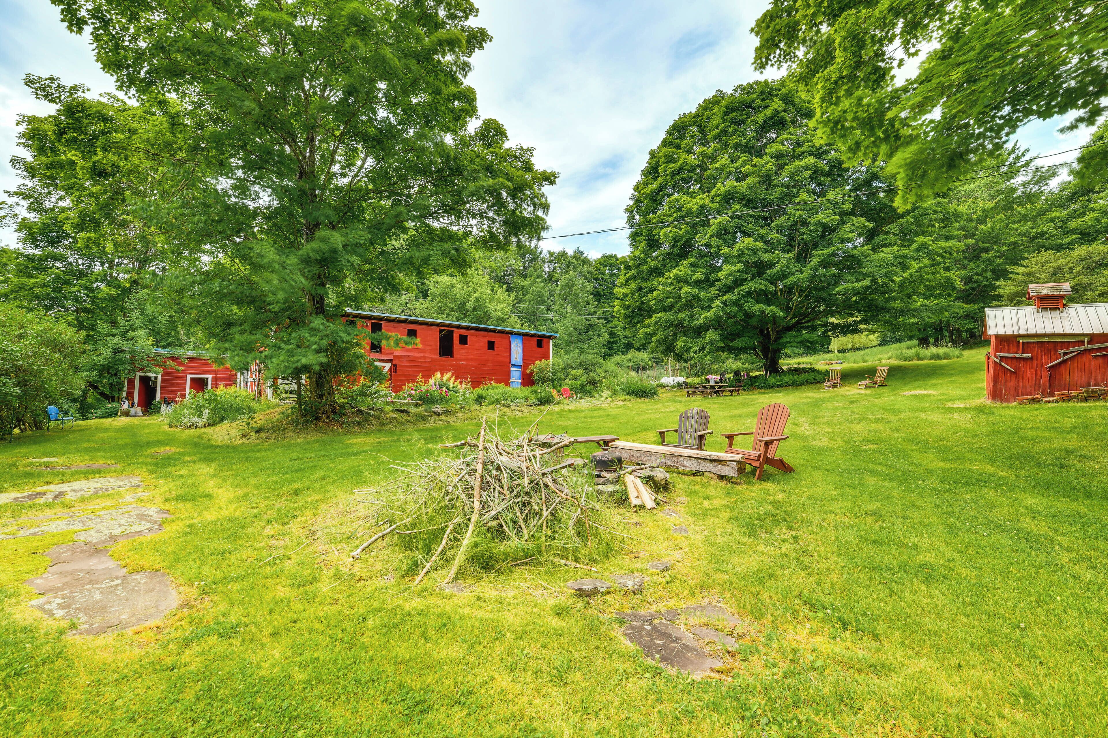 A rural property with a red barn, a small red house, and a large tree.