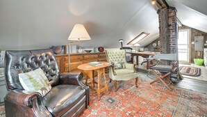 Un dormitorio estilo loft con sofá de cuero, un sillón verde, una mesa de madera y un tapiz estampado.