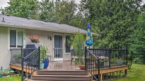 A house with a wooden deck, a barbecue grill, and potted plants.