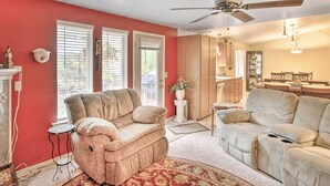 A living room with two sofas, a ceiling fan, and a dining area with a table and chairs.