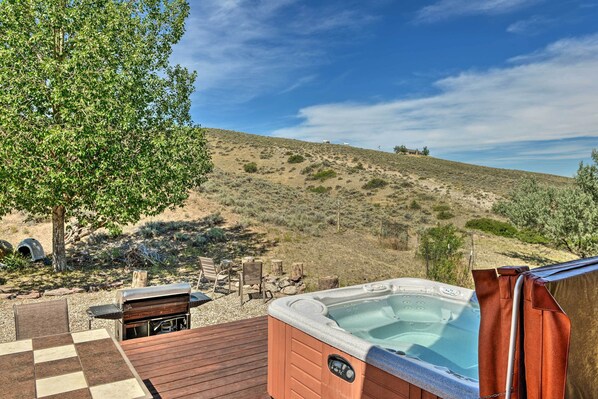 A hot tub on a wooden deck with a view of a hilly landscape.