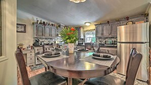 A modern kitchen with a dining area, featuring stainless steel appliances, wooden cabinets, and a central island with a vase of flowers. - Cozy Hale Home Between Long & Loon Lakes! (Hale)