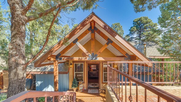 A wooden cabin with a brick porch, a staircase, and a metal railing. - Cozy Ruidoso Cottage w/ Deck - 10 Min to Village! (Ruidoso)