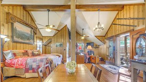 A cozy cabin interior with a wooden dining table, two beds, and a kitchen area. - Cozy Ruidoso Cottage w/ Deck - 10 Min to Village! (Ruidoso)