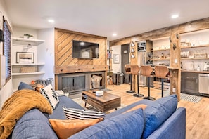 A modern living room with a fireplace, a flat-screen TV, and a dining area with bar stools. - Cozy-chic Keystone Getaway: 2 Mi to Slopes! (Keystone)