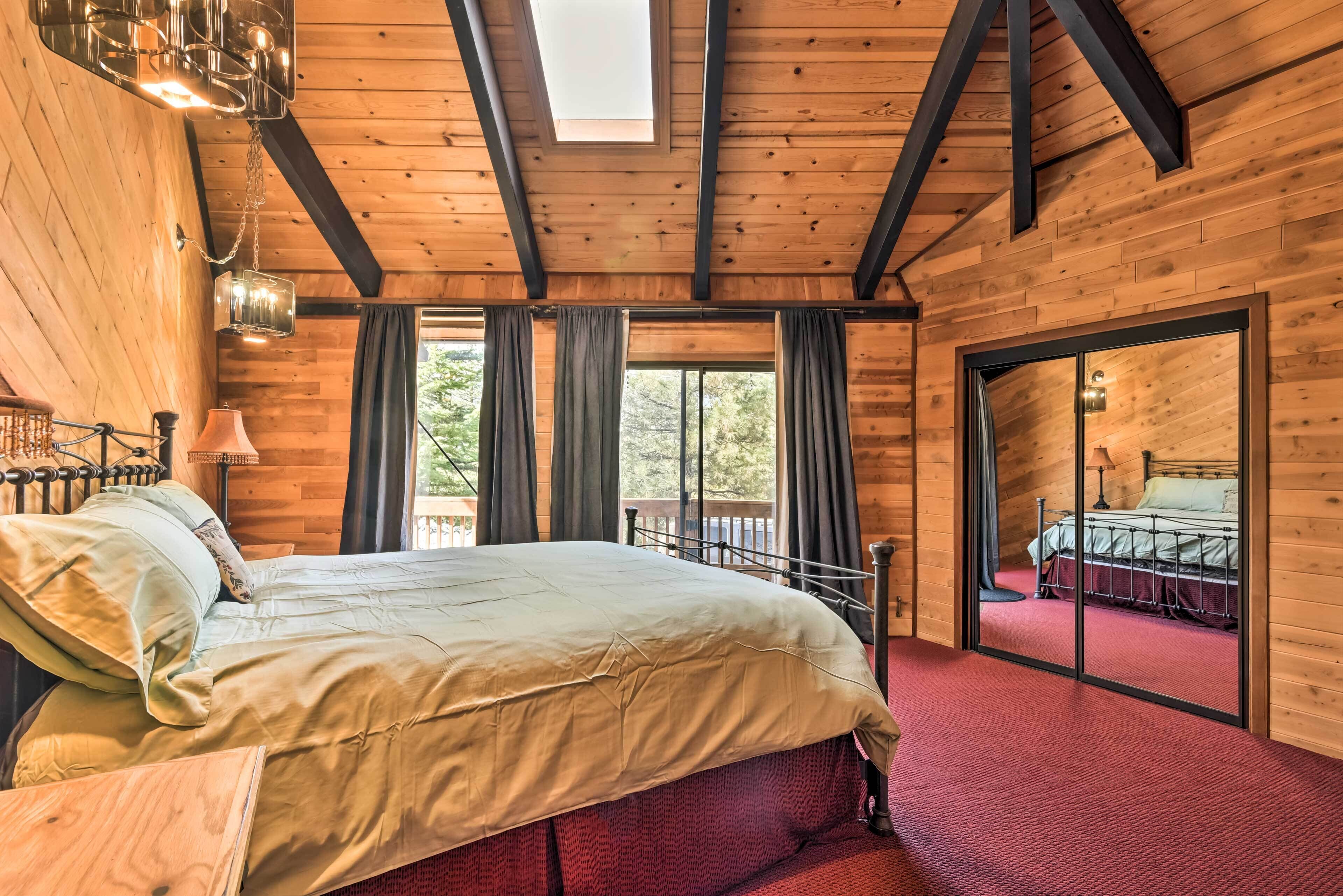 Camera da letto in una baita di legno con un letto grande, un balcone e vista sulla natura.