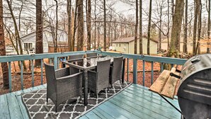 Une terrasse en bois avec des meubles en osier et un barbecue.
