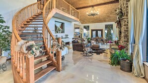 Un vaste espace de vie agrémenté d’un escalier en bois, d’un mur en pierre et d’un lustre.