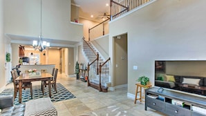 A spacious living area with a dining table, sofa, and TV stand.