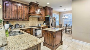 A kitchen with granite countertops, wooden cabinets, a built-in oven, and a refrigerator.
