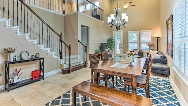 A spacious living area with a dining table, chairs, a sofa, and a staircase.