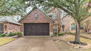 A residential house with a brick facade, a large garage door, and a well-maintained lawn.