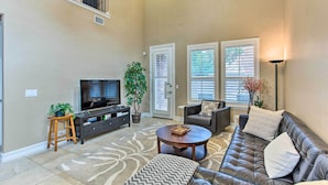 A living room with a leather sofa, a television, a coffee table, and a potted plant.