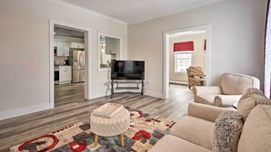 A modern living room with a flat-screen TV, a beige sofa, a patterned rug, and a wooden coffee table. - Dog-friendly Downtown Auburn Vacation Rental! (Auburn)