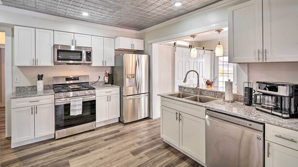 A modern kitchen with white cabinets, stainless steel appliances, and a wooden floor. - Dog-friendly Downtown Auburn Vacation Rental! (Auburn)