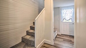 A staircase with carpeted steps leading to a landing with a white door and a window with a floral curtain. - Dog-friendly Downtown Auburn Vacation Rental! (Auburn)