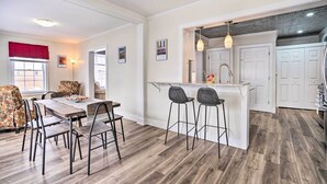 A modern kitchen with white cabinets, a bar area, and a dining space with a wooden table and metal chairs. - Dog-friendly Downtown Auburn Vacation Rental! (Auburn)