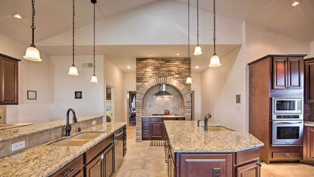 A spacious kitchen with granite countertops, a central island, and a stone fireplace. - Gettysburg Area Retreat, 12 Mi to Nat'l Park! (New Oxford)