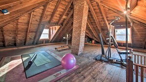 A spacious attic room with a sloped wooden ceiling, a brick column, and exercise equipment. - Gettysburg Area Retreat, 12 Mi to Nat'l Park! (New Oxford)