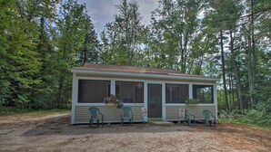 Een klein huisje met een veranda, twee stoelen en een bloempot.