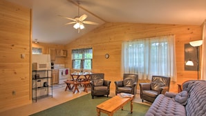 Een gezellig interieur van een chalet, met een eethoek, twee leren fauteuils, een houten bijzettafeltje en een bank.