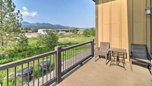 Un balcon avec vue sur les montagnes, une table et deux chaises.